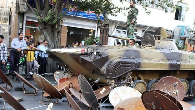 Iran security forces use an armoured vehicle to destroy satellite dishes