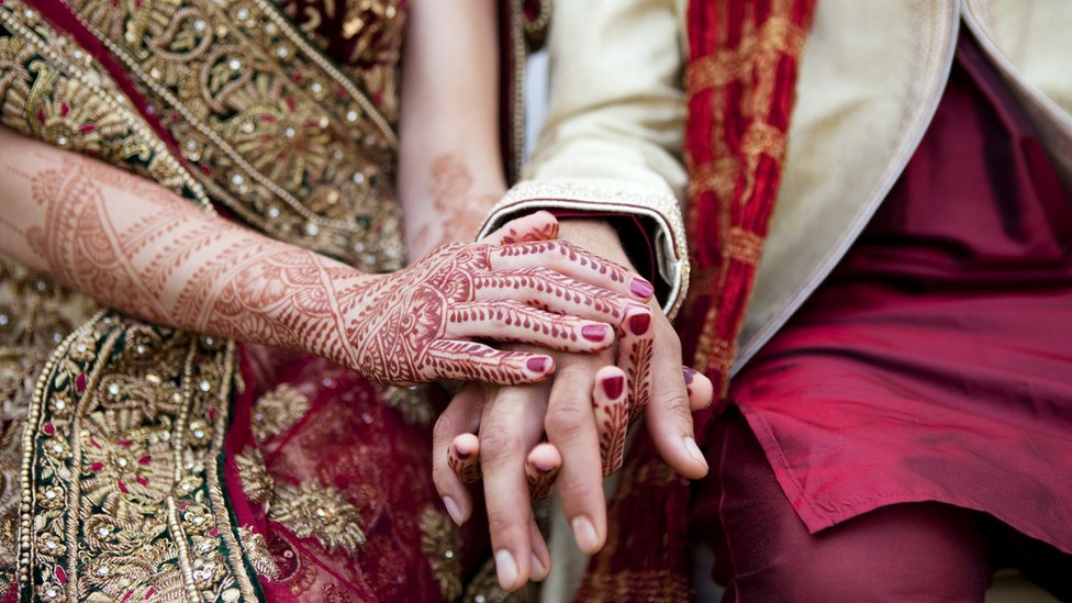 An Indian couple holding hands on their wedding day