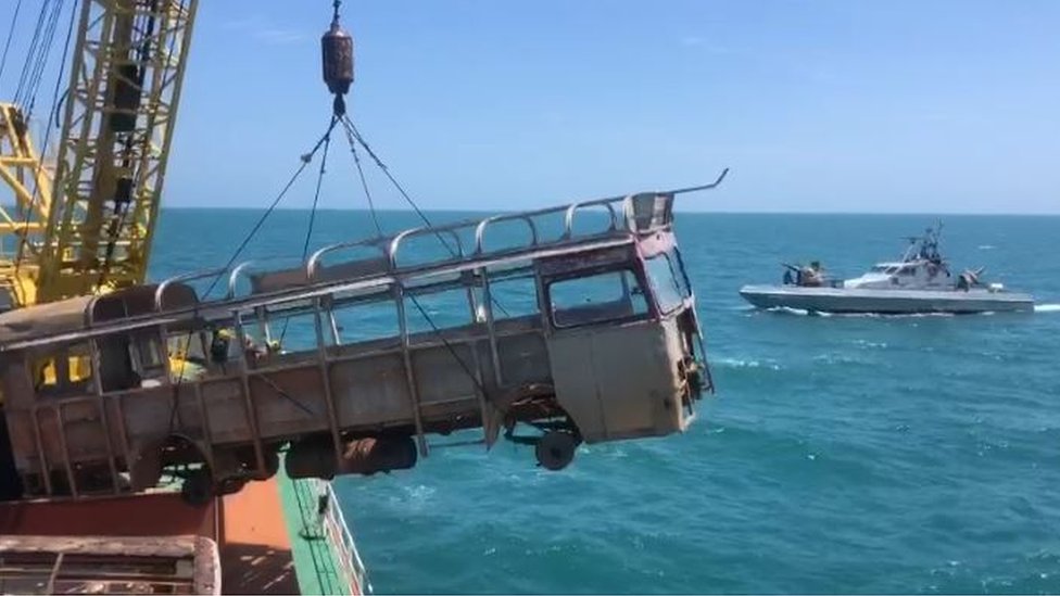 A boat dumping a old bus into the sea