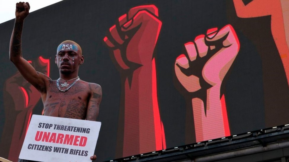 A protester gestures as he holds a placard at a live concert at the Lekki toll gate in Lagos, on October 15, 2020, during a demonstration to protest against police brutality and scrapping of Special Anti-Robbery Squad (SARS