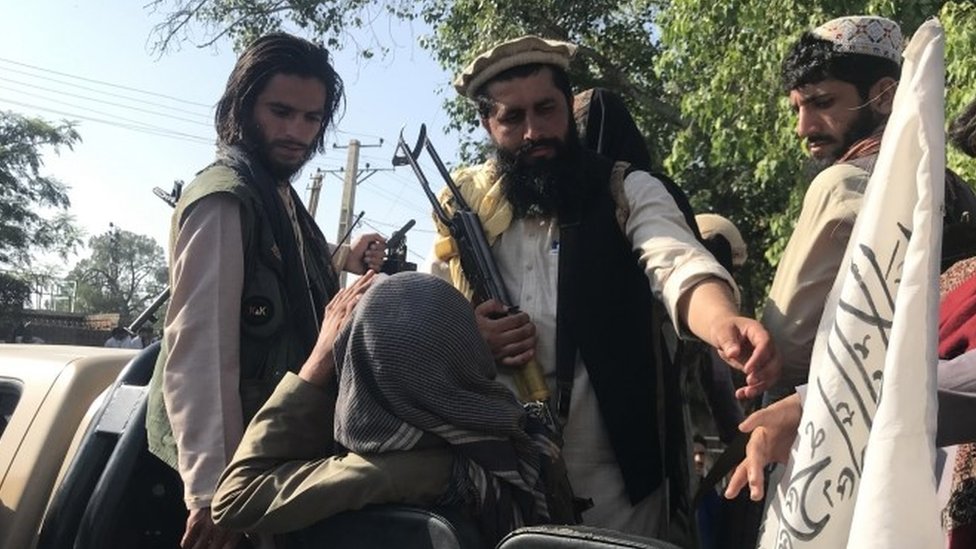 Taliban fighters displaying their flag on outskirts of Kabul on 15 August 2021