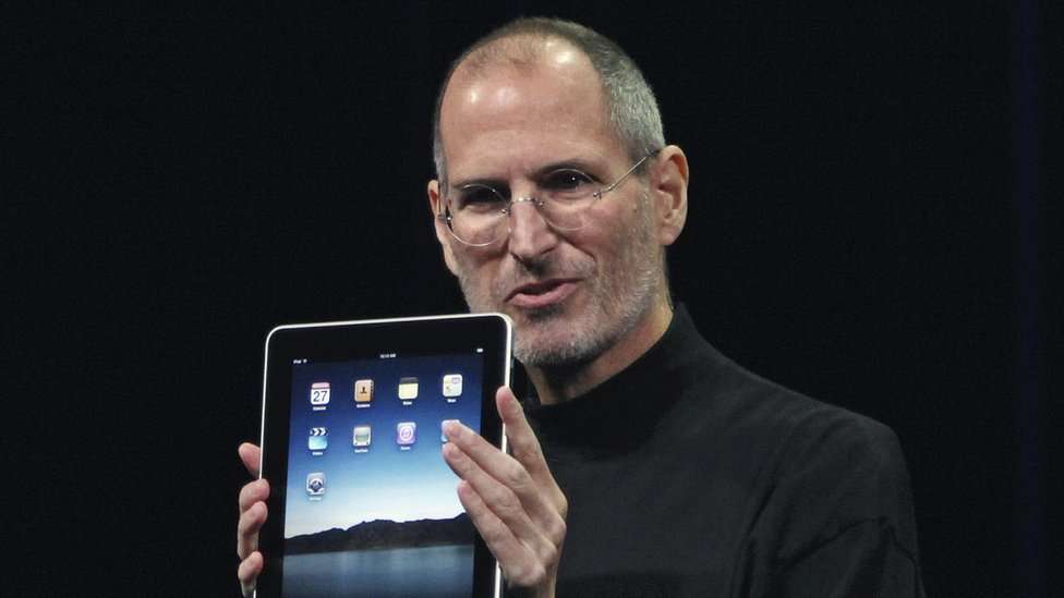 Steve Jobs holding an iPad on stage