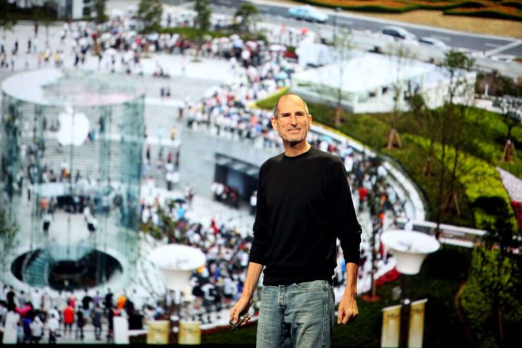 Steve Jobs standing in front of a projection of an ampitheathre