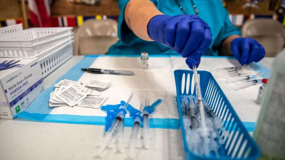 A nurse reaches for a needle.