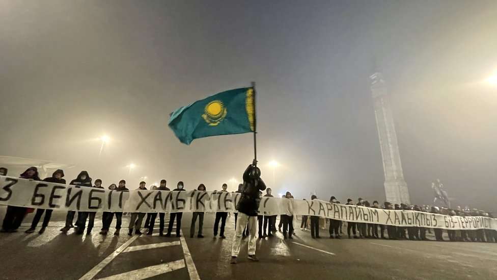 Protesters on Almaty's main square hold a banner saying 