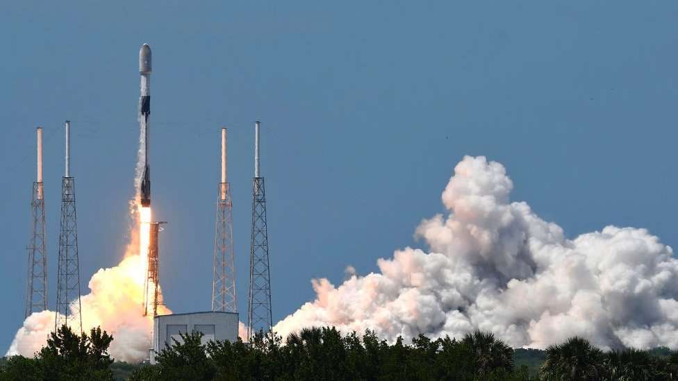 A rocket launches in a plume of smoke