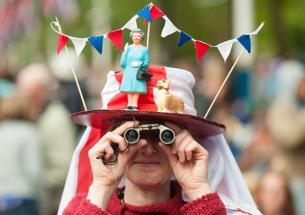 A woman in a fancy dress hat featuring Queen Elizabeth II and a corgi, pictured during the Diamond Jubilee concert at Buckingham Palace in 2012