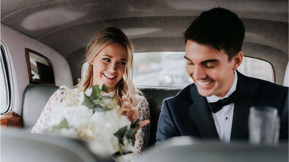 Pareja de recién casados dentro de un auto.