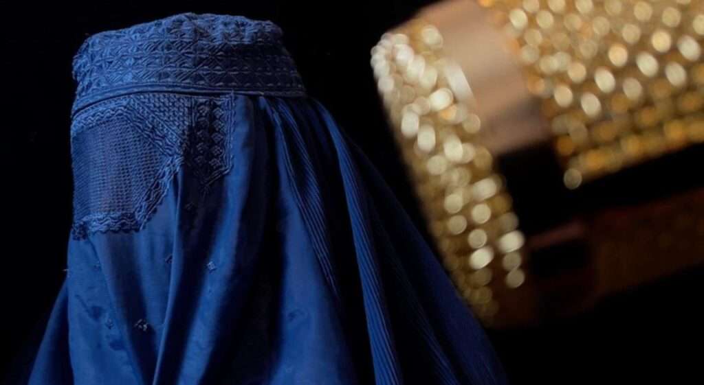 One of the sisters singing under a burka, with a microphone in front